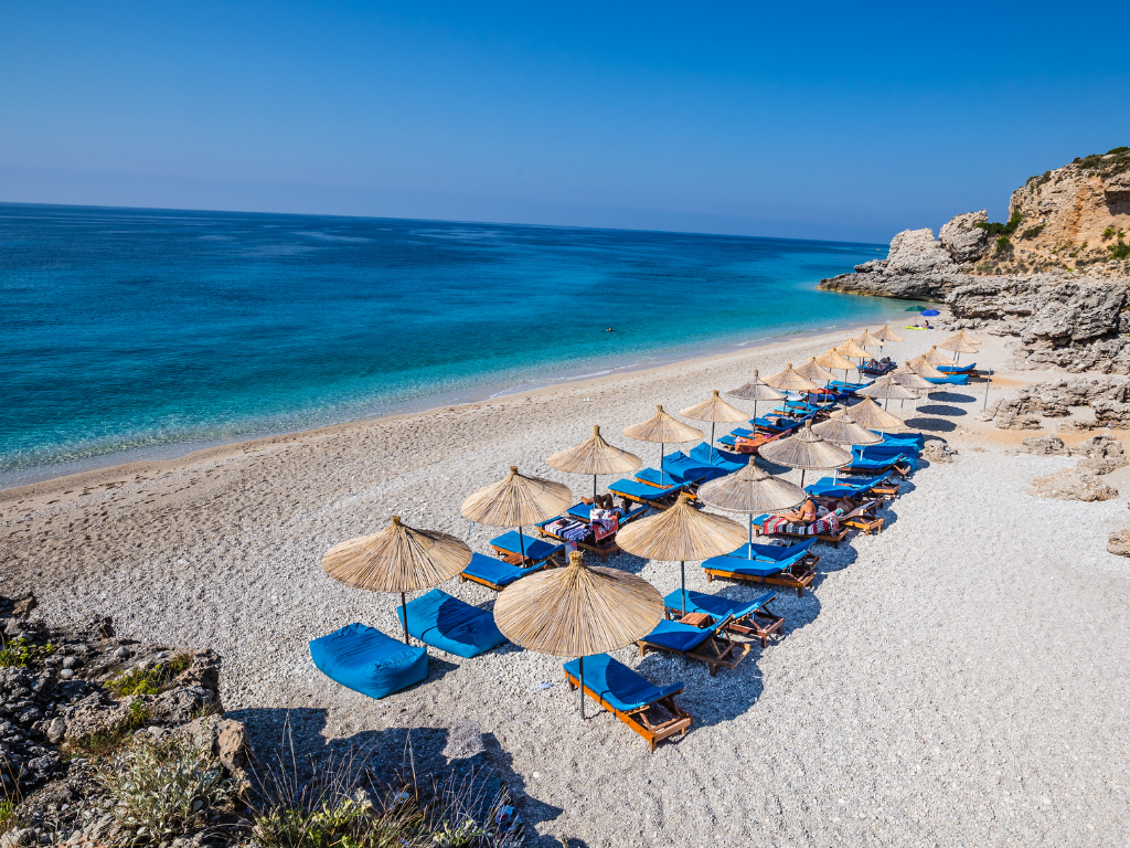 Crystal-clear water and pebbled shore at Dhërmi beach, part of Albanian Riviera group tours